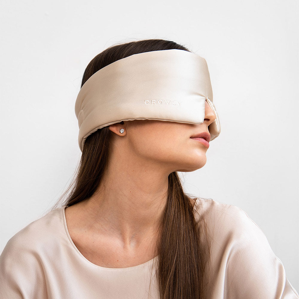 Model with beige coloured silk sleep mask over eyes